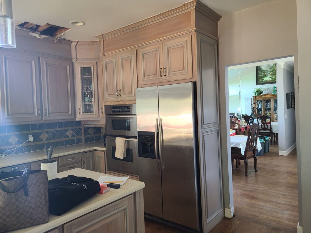Original kitchen cabinetry, ovens and doorway to the dining room