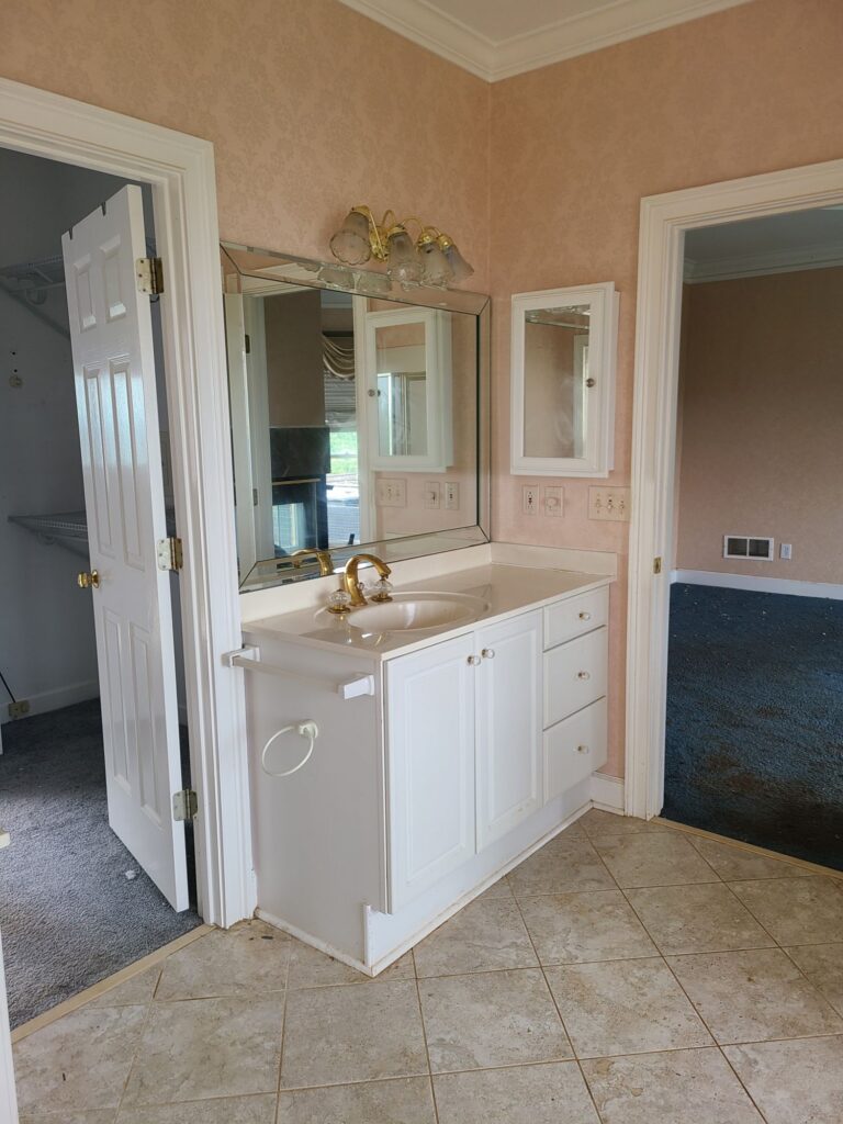 Original primary bathroom vanity between closet and bedroom doors