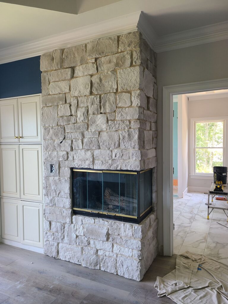 New corner stone fireplace beside built-in cabinets