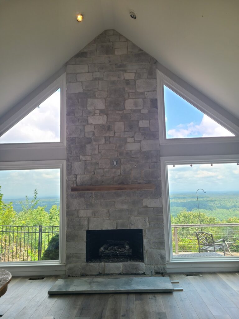 New floor-to-ceiling stone fireplace framed by mountain-view windows
