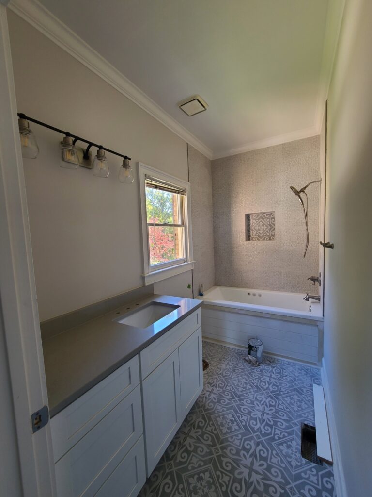 Renovated hall bathroom with patterned floor tile and soaking tub