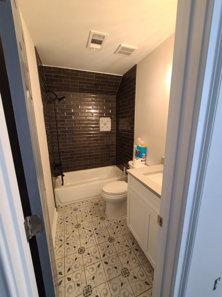 Basement bathroom with dark subway tile and patterned floor