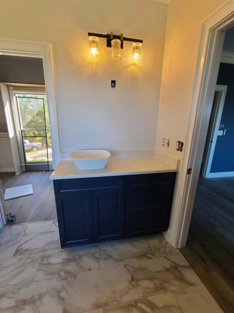 Navy vanity with vessel sink and marble-look tile