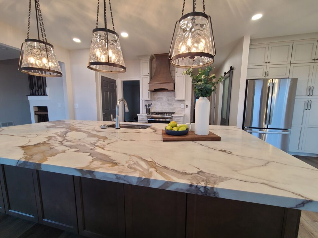 Finished kitchen island with pendants, range hood and pantry cabinets