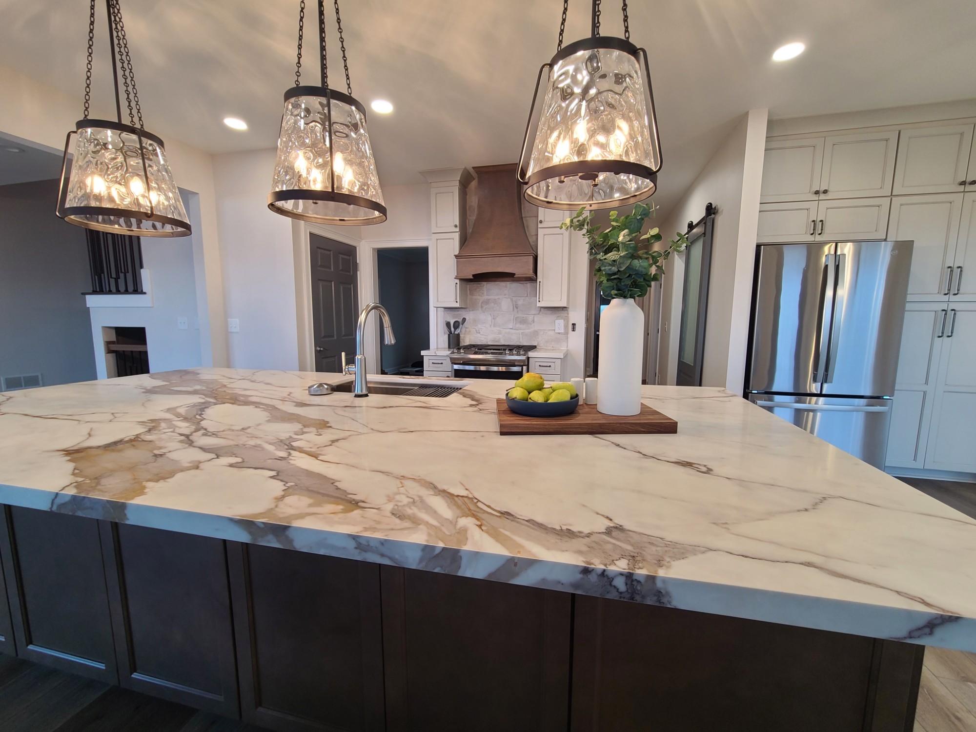 Finished kitchen island with pendants, range hood and pantry cabinets